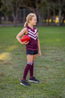 © Austockphoto - young blonde schoolgirl holding red leather football on playing field