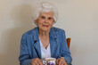 © Austockphoto - an elderly white-haired lady in her eighties sitting by herself with a cup of tea