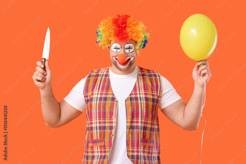 Young man as crazy clown with balloon and knife on orange background