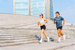 © muse studio - Couple jogging on urban steps with modern buildings in the background during a sunny day