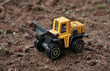 © thebaikers - Yellow wheel loader or tractor toy on soil or ground background. construction image concept with heavy equipment.