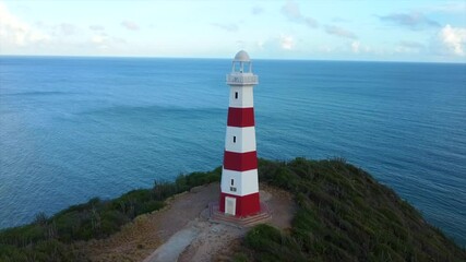 Wall Mural - A lighthouse is on a hill overlooking the ocean