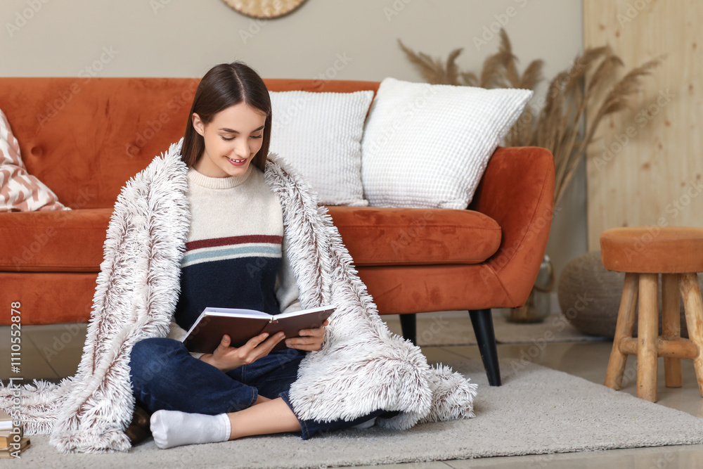 Young woman reading book while sitting on floor in living room