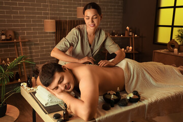 Wall Mural - Young man undergoing treatment with sea salt in dark spa salon