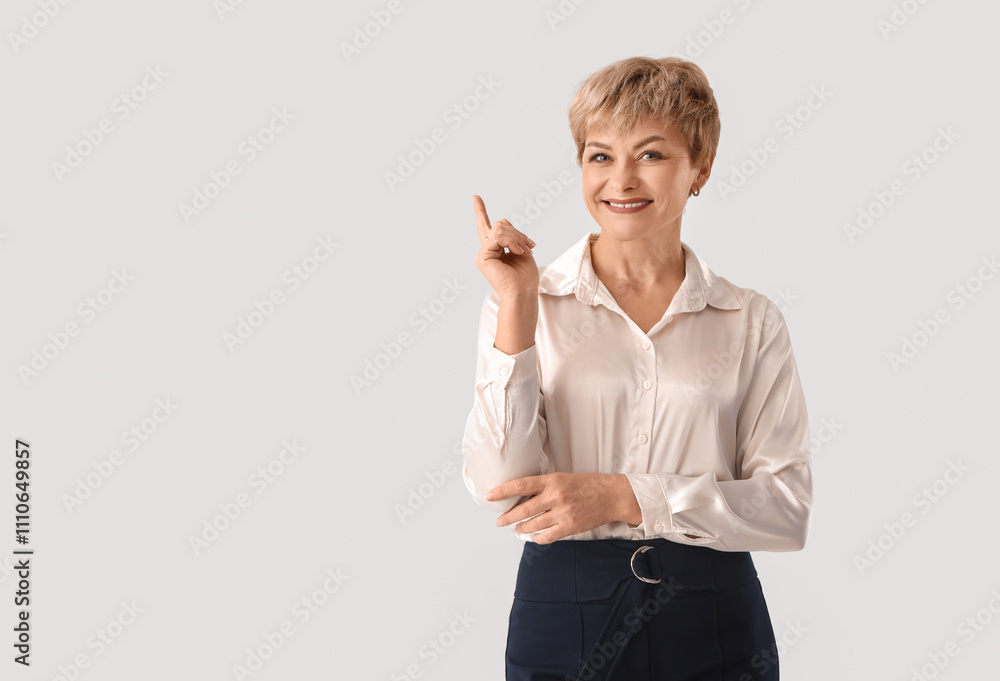 Mature businesswoman pointing at something on white background