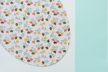 Poster - detail of a large ovoid shape machine-cut from decorative scrapbooking paper with florals and blue band on blank paper