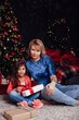 © dmitriisimakov - Mother with daughter at Christmas tree with gifts garlands decorated for the new year