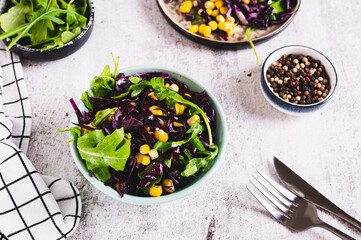 Wall Mural - Vegetarian salad of purple cabbage, corn and arugula in a bowl on the table