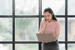 © Kritdanai - Focused Young Woman Working on Laptop by Window