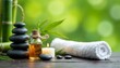© schiers_images - Serene spa image featuring a lit aromatherapy candle, massage oil, smooth balance stones, and a fluffy white towel. The soothing ambiance is set against a natural green background, creating a tranquil