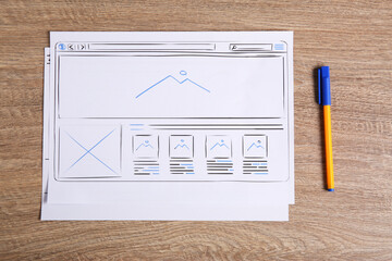Wall Mural - developing ui design. sketches of website wireframes and pen on wooden table, top view