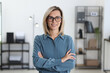 © New Africa - Portrait of happy businesswoman with crossed arms in office