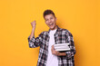 © New Africa - Young student with stack of books happy about his good exam result on yellow background