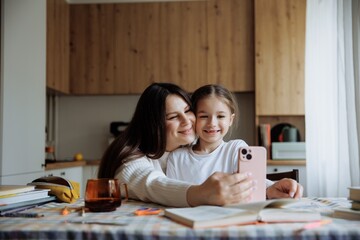 mom and daughter take a selfie at home at the kitchen table