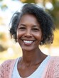 © Johannes - Portrait of smiling middle aged african woman looking at camera. Cheerful black mid adult woman smiling outdoor. Close up face of beautiful black lady laughing at park.