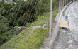© wagner - Rainwater collection network in car parking area with ditch, manhole with metal grid cover and drainage pipe that crosses metal wire fence into forest area