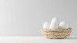 © Keopaserth - Fresh white eggs in small straw basket on clean surface, creating minimalist and serene atmosphere. Perfect for culinary or decorative use