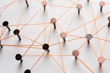 Network connection. Nails linked together by thread on white table, above view