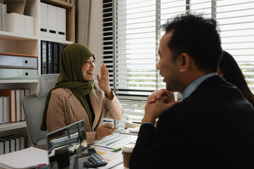 Wall Mural - group of businessmen are discussing in an office. businessmen of different culture are meeting to make products that are appropriate and religiously correct. A businesswoman is wearing a hijab.