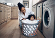 © peopleimages.com - Mom, baby and playing with laundry basket in home, helping and multitasking with chores. Mother, support daughter and housekeeping with child in kitchen, cleaning and clothes for washing machine