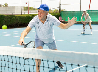 Wall Mural - Portrait of emotional aged man enjoying friendly tennis match at outdoors court