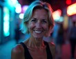 © Eva - A 60 year old Caucasian woman with short blonde hair wearing a black sleeveless top, smiling at the camera, closeup face