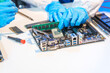 © NanSan - Close-up of a technician wearing gloves soldering electronic components at a desk in an office. The scene highlights precision, technical expertise, and focused work in an electronics lab setting