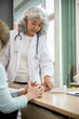 © Kittipong - A professional senior Asian female doctor in a uniform having a consultation with a young married couple in the examination room. doctor visit, health care, medical