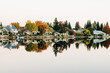 © Cavan Images - Tranquil fall scene with houses and trees reflected in water
