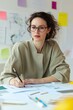 © Iryna - A woman is sitting at a desk with a pencil and a piece of paper. She is writing on the paper and she is focused on her work. The scene suggests a professional or creative environment