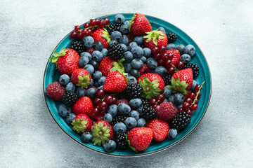 Wall Mural - Mix of ripe colorful berries in bowl photography . Blueberry , strawberry , raspberry , blackberry and red currant . Top view