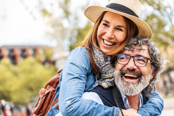 Happy senior couple having fun walking on city street - Two older tourists enjoying together weekend summer vacation - Life style, tourism and romance moments concept