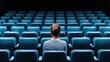 © taweesak - A young woman sitting in a darkened theater, the empty seats surrounding her emphasizing her loneliness and sorrow