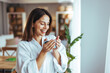© Dragana Gordic - Smiling Woman Enjoying Morning Coffee in Cozy Home Environment