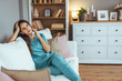 © Dragana Gordic - Smiling Woman in Scrubs Relaxing on Comfortable Sofa at Home