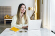 © muse studio - Young woman working on a laptop at a bright, modern workspace with minimal decor