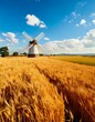 © FCEalin  - Peaceful rural countryside with fields of golden wheat and a windmill under a blue sky.