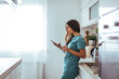 © Dragana Gordic - Healthcare Professional Relaxing With Phone and Drink in Kitchen