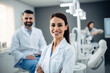 © FoxTok - Young girl dentist in medical clothes smiling and looking at camera against background of dentist chair in clinic office. Dental health concept, treatment, orthodontists, medicine