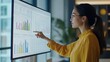 © Lion - young woman pointing at data on a large monitor with charts in a modern office bright natural light filling the room