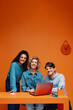 © Jacob Lund - Diverse team of adults posing and smiling with a laptop in a vibrant, dynamic, and colorful office setting