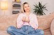 © Tatyana Gladskih - Adult woman sitting on the sofa at home and having a cup of coffee