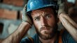 © Vuvimages - A construction worker with a blue hard hat and gloves looks concerned and introspective, symbolizing responsibility and the challenges of manual labor at job sites.