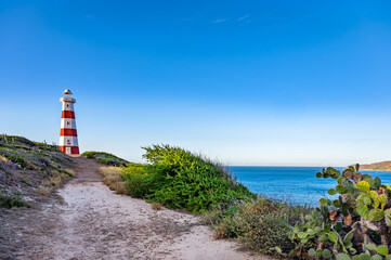 Wall Mural - A lighthouse is on a hill with a clear blue sky