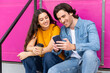 © VISTA by Westend61 - Smiling man sharing smart phone with woman having coffee on steps
