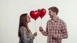 © Ivan - Two people stand close together holding bright red heart-shaped balloons. They share smiles and joy in a softly lit space, capturing a moment of connection and affection