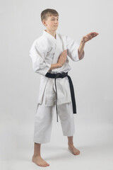 Fifteen year old male teenage karate black belt open hand block, studio shot against a white background