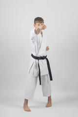 Wall Mural - Fifteen year old male teenage karate black bel in sanchin stance doing a back fist , studio shot against a white background