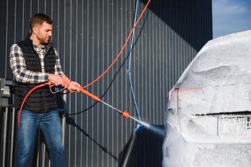 Wall Mural - Car is washed at a professional car wash. Man washes a car with foam. Detailing