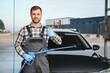 © Serhii - Man worker washing car service. Car wash cleaning station high pressure water. Employees clean a vehicle professionally
